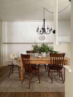 a dining room table with chairs and a chandelier hanging from the ceiling above it