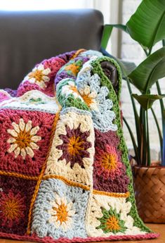 a crocheted blanket sitting on top of a table next to a potted plant