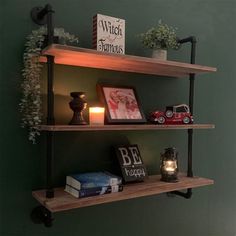 two wooden shelves with candles, books and pictures on them against a green painted wall