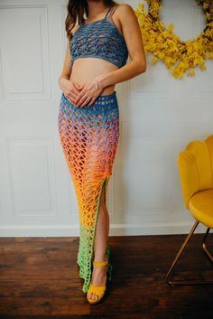 a woman standing in front of a wall wearing a rainbow colored skirt and crop top