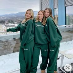 three women in matching green sweat suits posing for the camera with their arms around each other