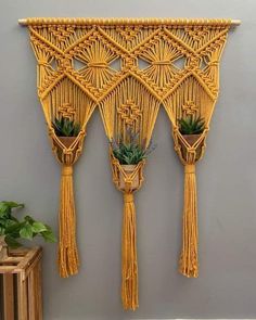 three yellow wall hangings with plants in them