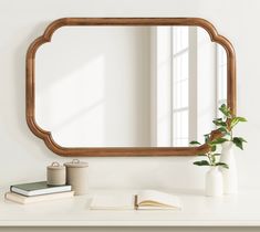 a mirror sitting on top of a white table next to a vase with a plant