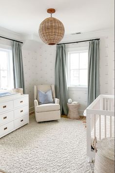 a baby's room with a crib, dresser and chair