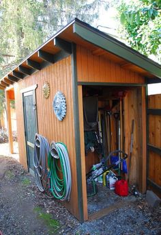 an outhouse with many tools in it and some hoses hanging from the roof