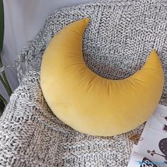 a banana shaped pillow sitting on top of a blanket next to a plant and magazine