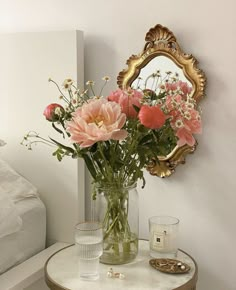 a vase filled with pink flowers sitting on top of a table next to a mirror