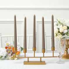 candles are arranged on a table with flowers in the background