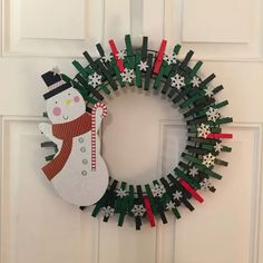 a christmas wreath made out of clothes pins with a snowman on the front door