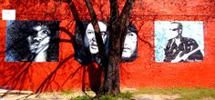 a red brick wall with several pictures on it and a tree in front of it