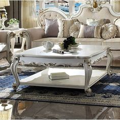 a living room filled with white furniture and lots of pillows on top of a rug