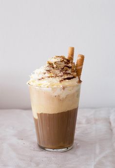 there is a drink with whipped cream and cinnamon sticks in it