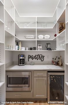 a kitchen with lots of white shelves and silver appliances