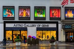 people are walking in front of the astro gallery of gems store on a rainy day