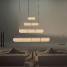 several lights hanging from the ceiling in a room with concrete mounds on the floor and one suspended above them