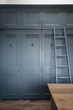 an empty room with blue lockers and ladder