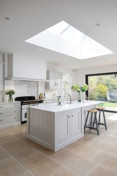 a large kitchen with an island in the middle and two stools at the end