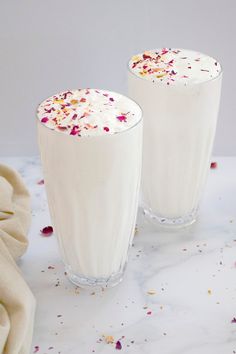 two glasses filled with whipped cream and sprinkles on top of a table