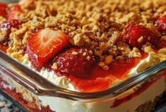 a dessert with strawberries and crumbled toppings in a glass casserole dish