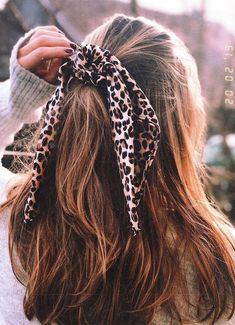 a woman with long hair wearing a leopard print scrunch style bow in her hair