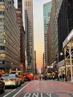 a city street filled with lots of tall buildings next to traffic and people walking on the sidewalk