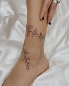 a woman's foot with a flower tattoo on her left leg and the bottom part of her ankle