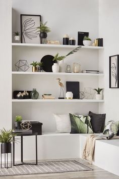 a living room filled with lots of furniture and plants on top of white shelving