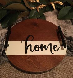 a wooden sign that says home on it next to some plants and rugs in the background