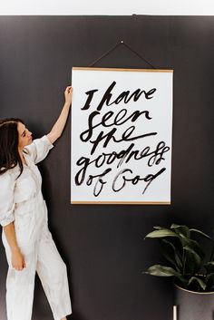 a woman standing next to a black and white wall with a sign hanging on it