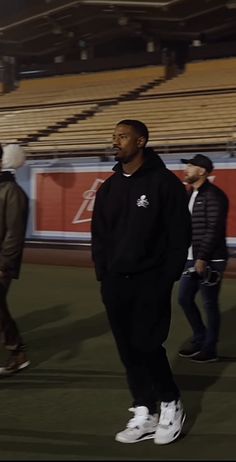 a man standing on top of a soccer field next to other men in black jackets