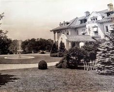 an old black and white photo of a large house with a fountain in the front yard