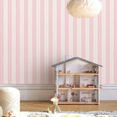 a doll house sitting on top of a wooden floor next to a wallpapered wall