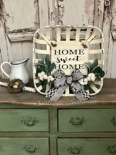 a green dresser with a white basket on top and a sign that says home sweet home