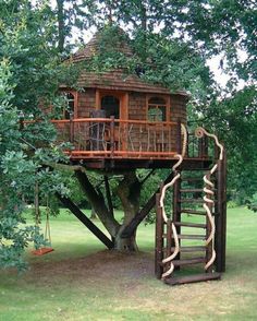 a tree house built into the side of a tree in a field with trees around it