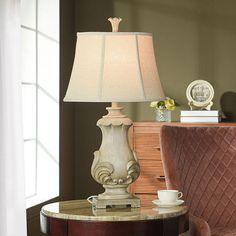 a table with a lamp on top of it next to a chair and sideboard