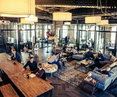 a group of people sitting around a living room with couches and tables in front of them