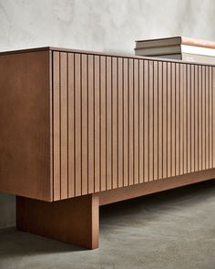 a wooden bench with books on top of it in front of a white wall and concrete floor