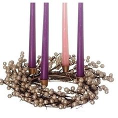 three candles are sitting next to each other with silver balls on them and one candle is lit