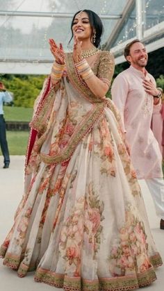 a woman in a white and pink lehenga dancing with other people behind her