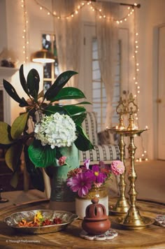 a table topped with plates and vases filled with flowers next to a candle holder