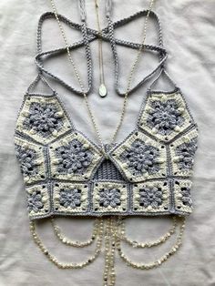 a crocheted top with chains hanging from it's sides and beads on the bottom