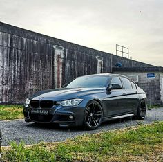 a black car parked in front of a building on a gravel road next to grass