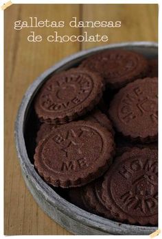 chocolate cookies in a metal bowl on a wooden table with the words galaetas daneas de chocolate