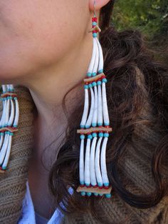 a woman wearing white and blue beaded earrings with long fringes on her ear