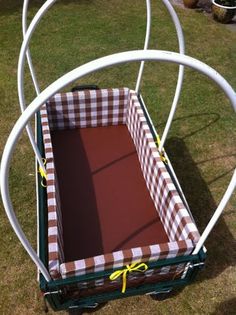 an empty cart with a checkered cloth in it sitting on the grass next to some potted plants