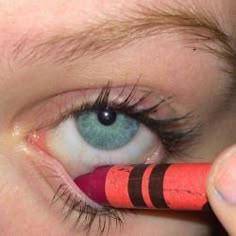 a woman is holding a pencil to her eye