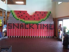 there is a giant watermelon sign made out of soda cans in the store