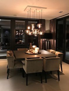 a dining room table and chairs with lights hanging from the ceiling in front of them