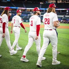 the baseball players are walking on the field during the game, and they are all dressed in white and red