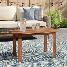 a wooden table sitting on top of a blue rug next to a couch and coffee table